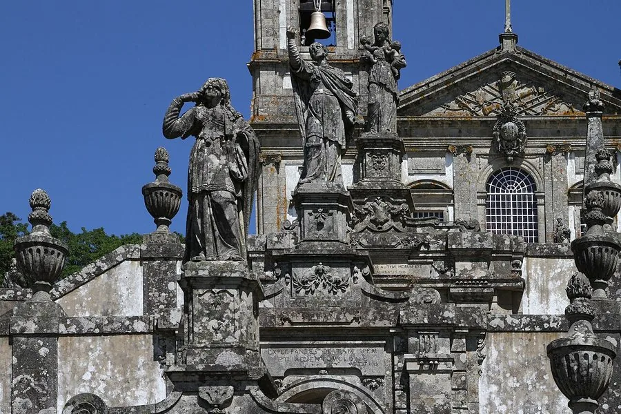 Figuras de granito y urnas en la escalinata bajo un cielo despejado